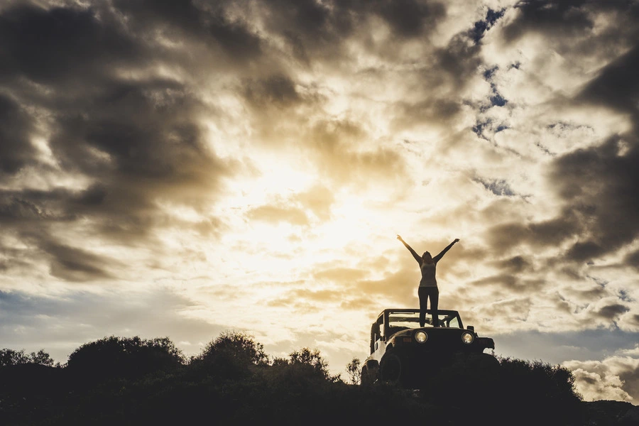 female standing on her car with the motivation for success