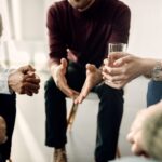 group of men and women seated in group therapy session discussing the 3 benefits of IOP to know about