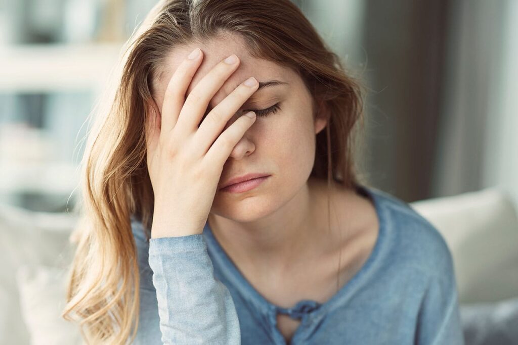 young woman looking exhausted as she struggles to identify triggers and warning signs of bipolar disorder