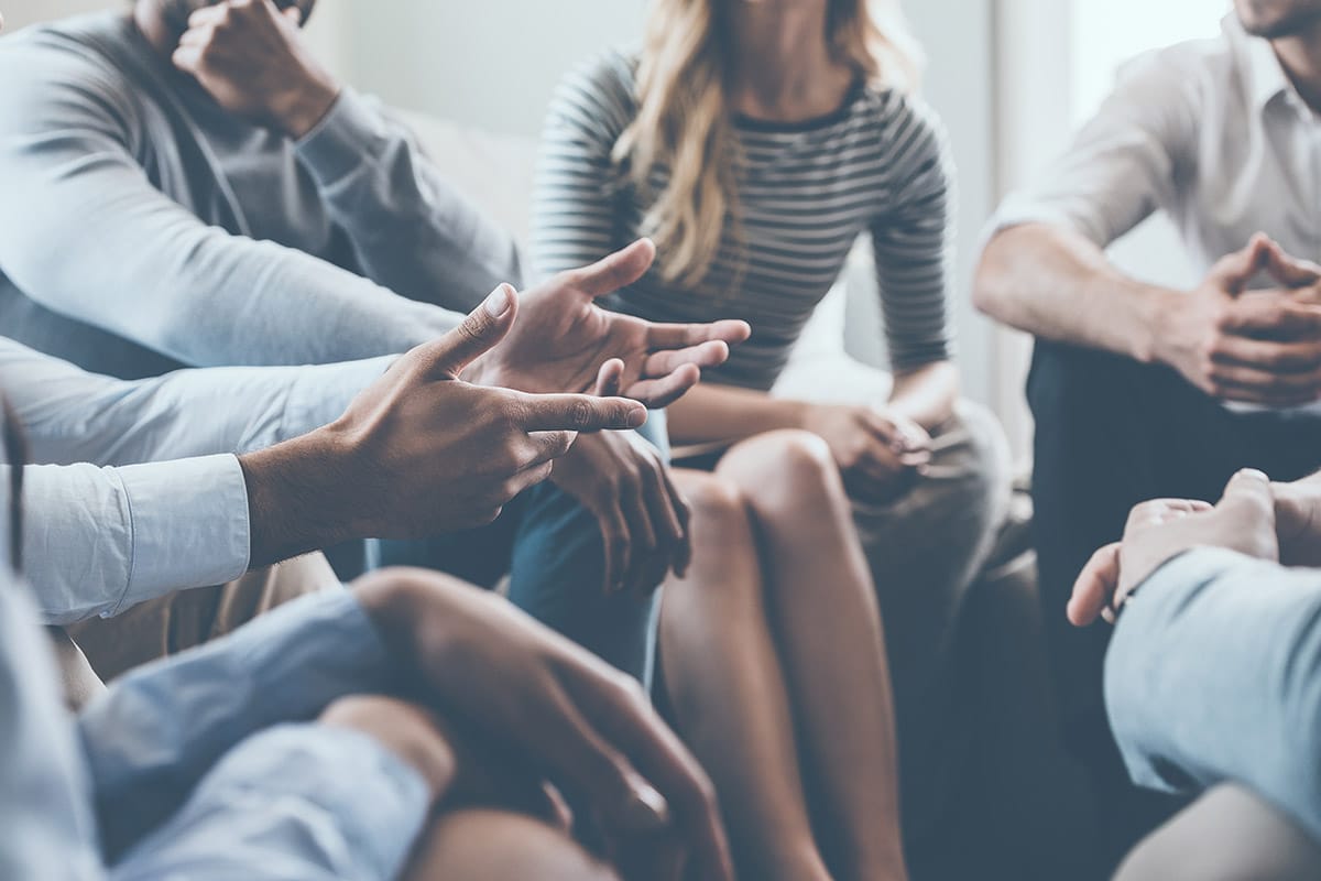 group of men and women seated in a circle discovering the power of support and how a group therapy program can help