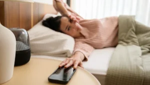 How to Reduce Morning Anxiety - woman snoozing alarm in bed