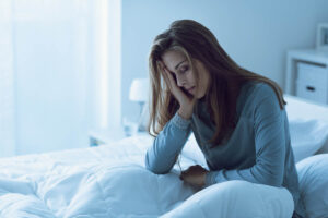 young woman seated on her bed with her head in her hands wondering what are the symptoms of cocaine withdrawal?